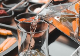 persona-vertiendo-agua-vaso-naranjas-cuchara_550617-100934